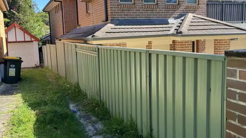 Eucalypt colour colorbond-style steel fence installed along a Perth residential side boundary with brick house and garden walkway