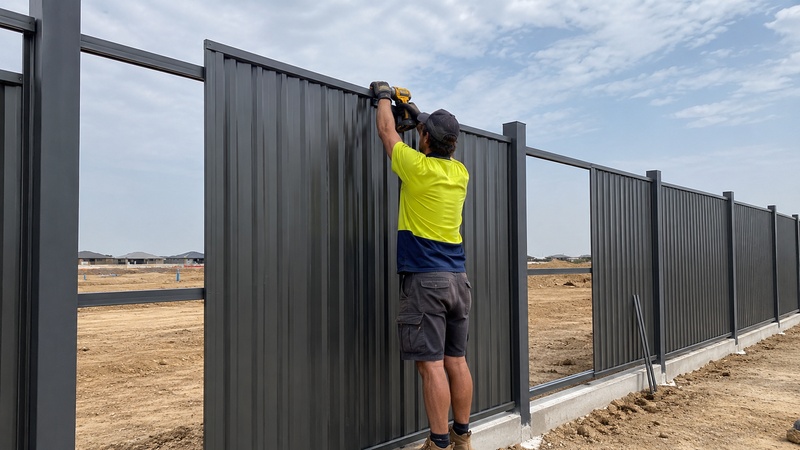Installing Colorbond-style fence panels with steel posts rails and caps as a modular fencing system